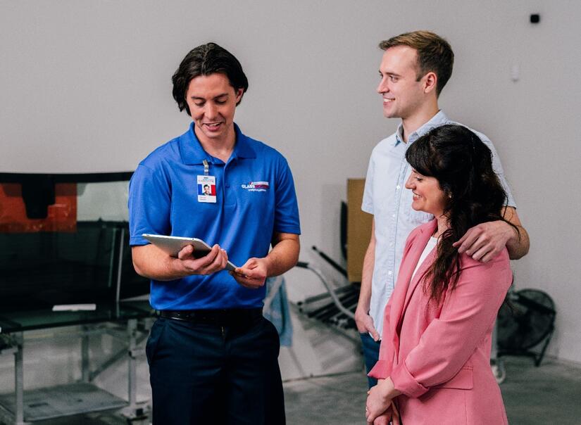 woman, man and glass specialists standing together and reviewing the door closer repair service on an iPad that the glass specialist is holding